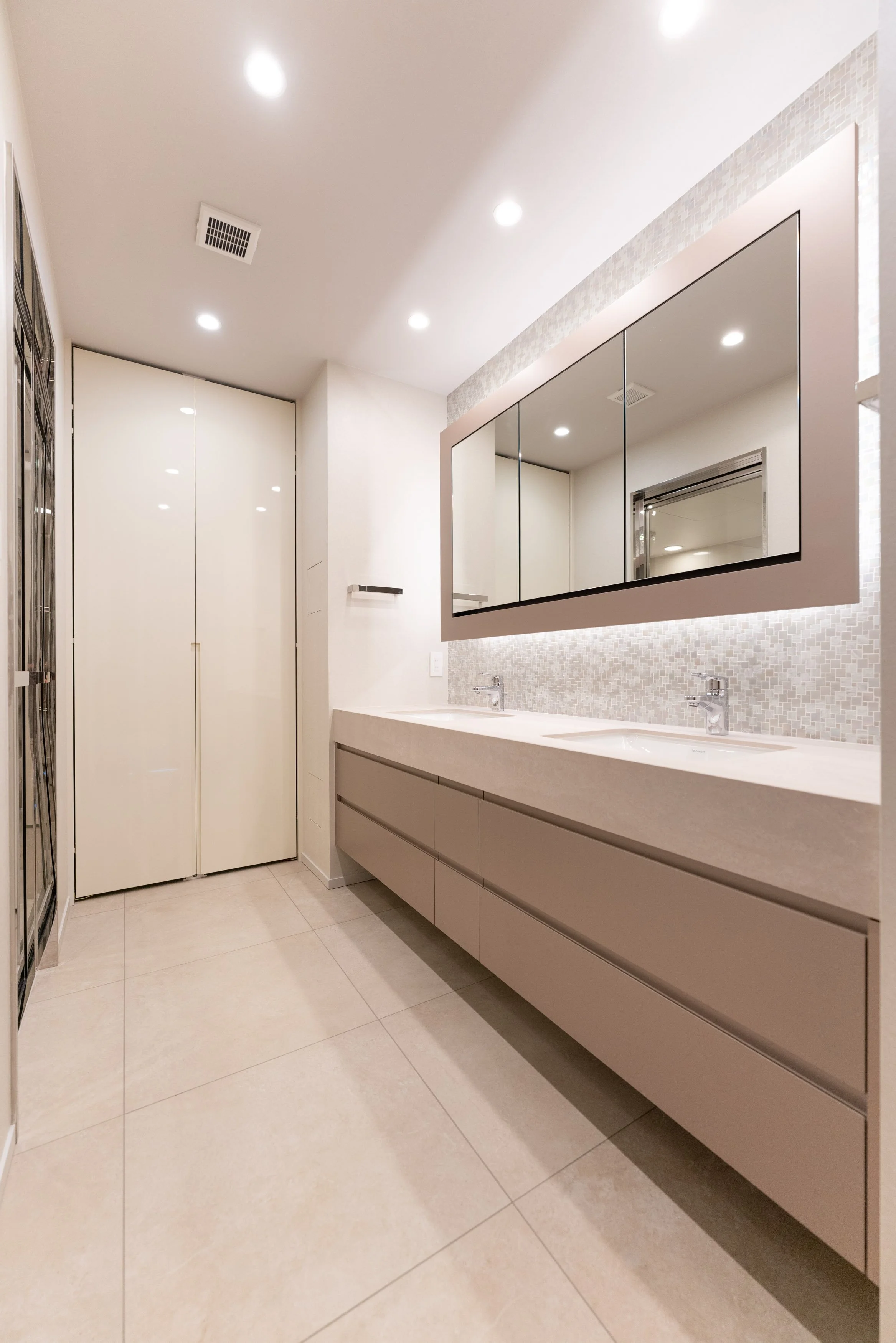 白い洗面台と鏡、タイルの壁、天井に照明があります。