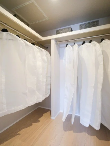 白い布でできた個室または仕切り。ハンガーにかけられた白衣やガウンのような衣服が掛かっている。