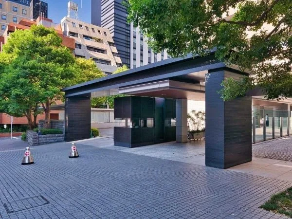 都市の中にある現代的な建物の入り口と周囲の街並み、木のある景色。