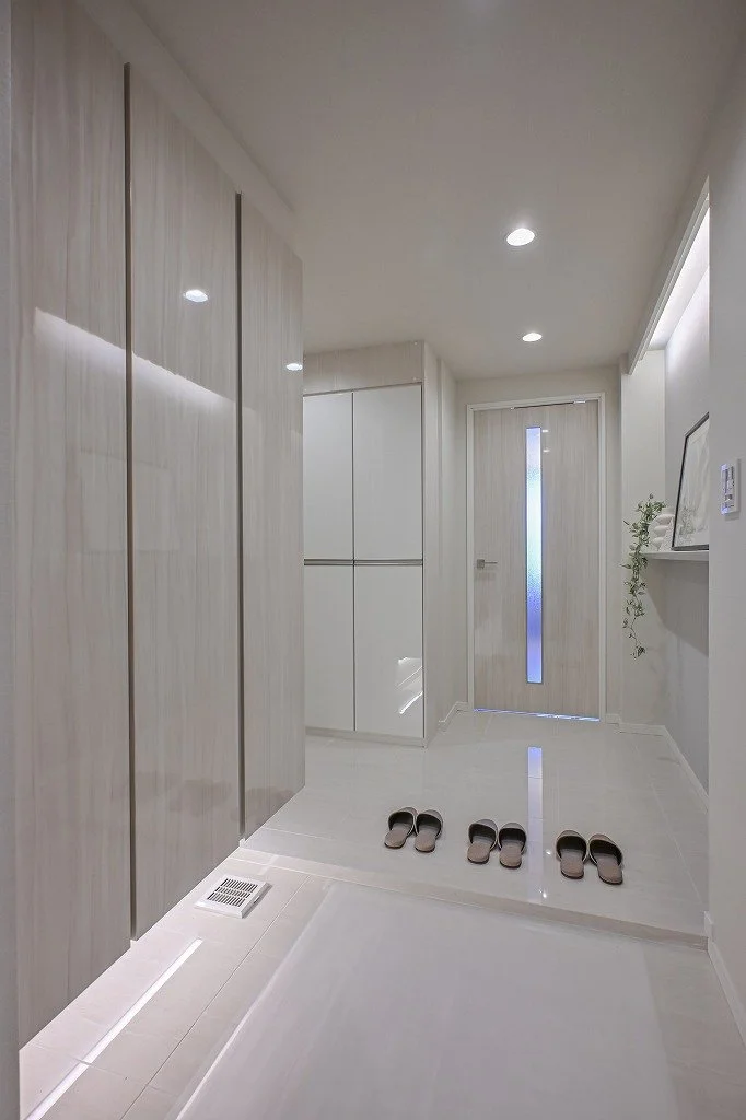 白を基調としたモダンな玄関、靴が3足置かれている