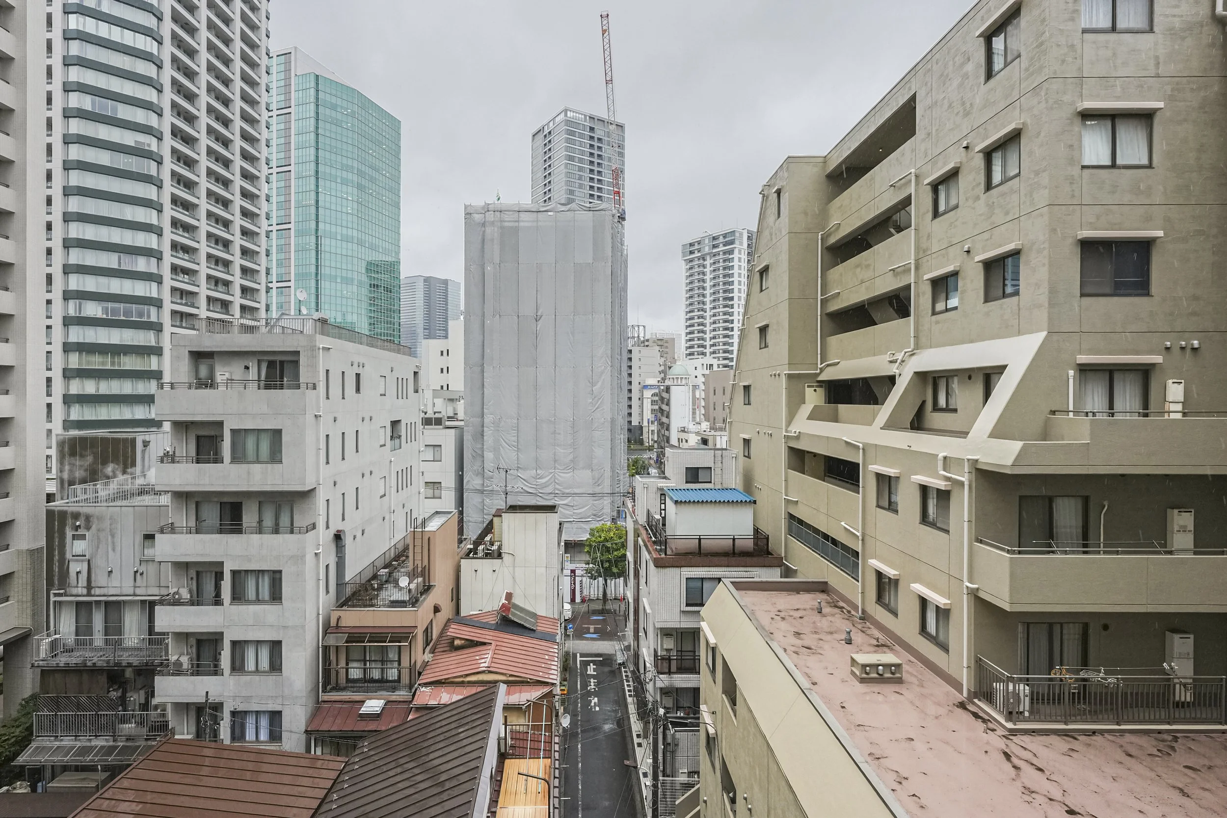 都市の高層ビルと住宅が並ぶ街並み、曇り空の空模様