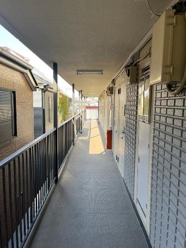 二階の通路の写真。手すりと扉が並び、屋外の景色が見える。