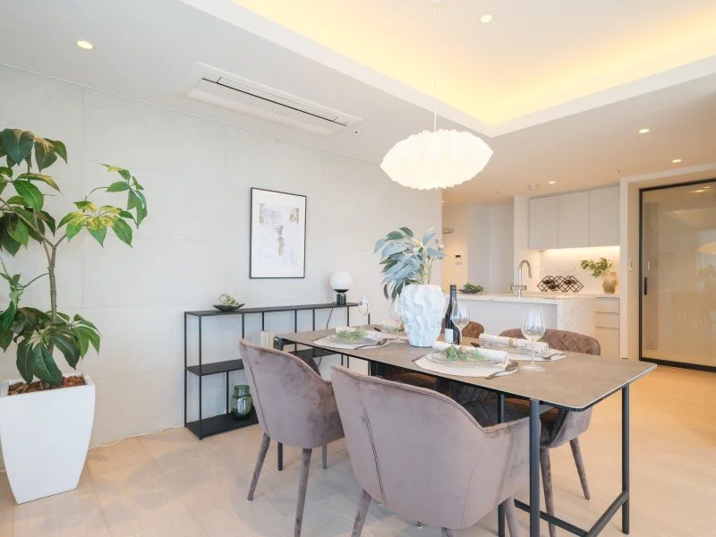 モダンなダイニングルームとキッチンのインテリア。大きな植物とシンプルな装飾が特徴的。