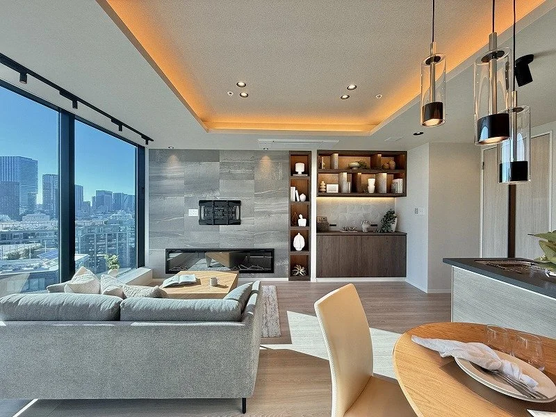 都会の高層ビルが見える大きな窓のあるモダンなリビングルームの interior, ソファ、丸いダイニングテーブルと椅子、壁に飾られた棚と装飾品、暖色照明。