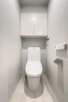 白いトイレと棚がついた小さなトイレルーム