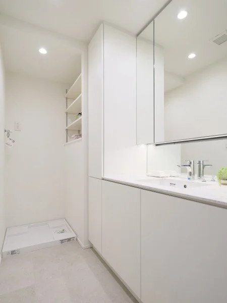 白い洗面台と鏡、収納棚がある洗面所