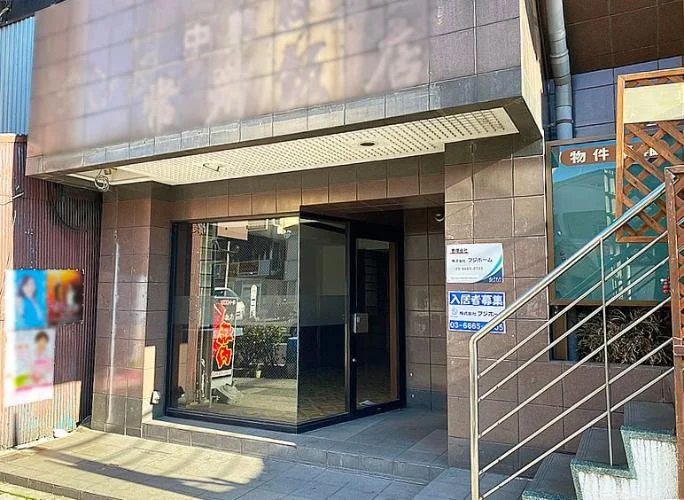 建物の入り口のガラスドアと窓、サインがある外観。