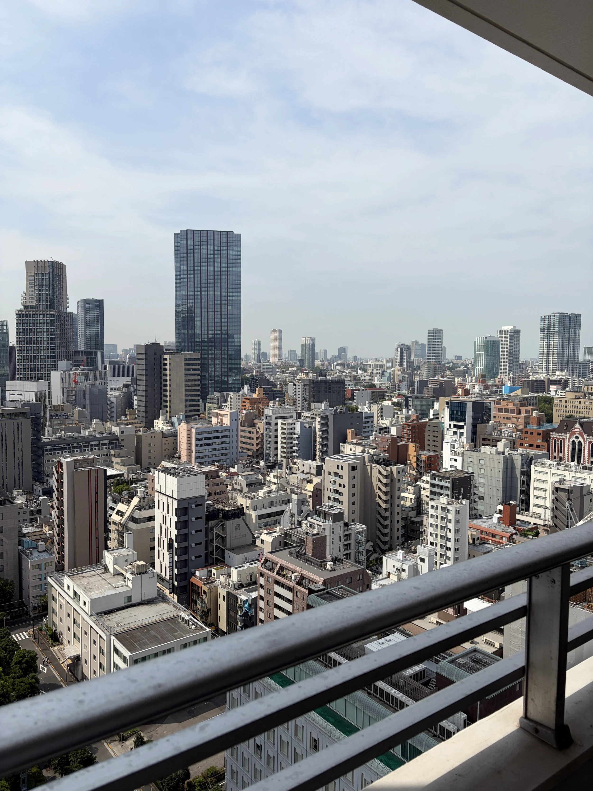 高層ビル群と都市の景観。手すり越しに見える都市の道路や建物が並ぶ風景