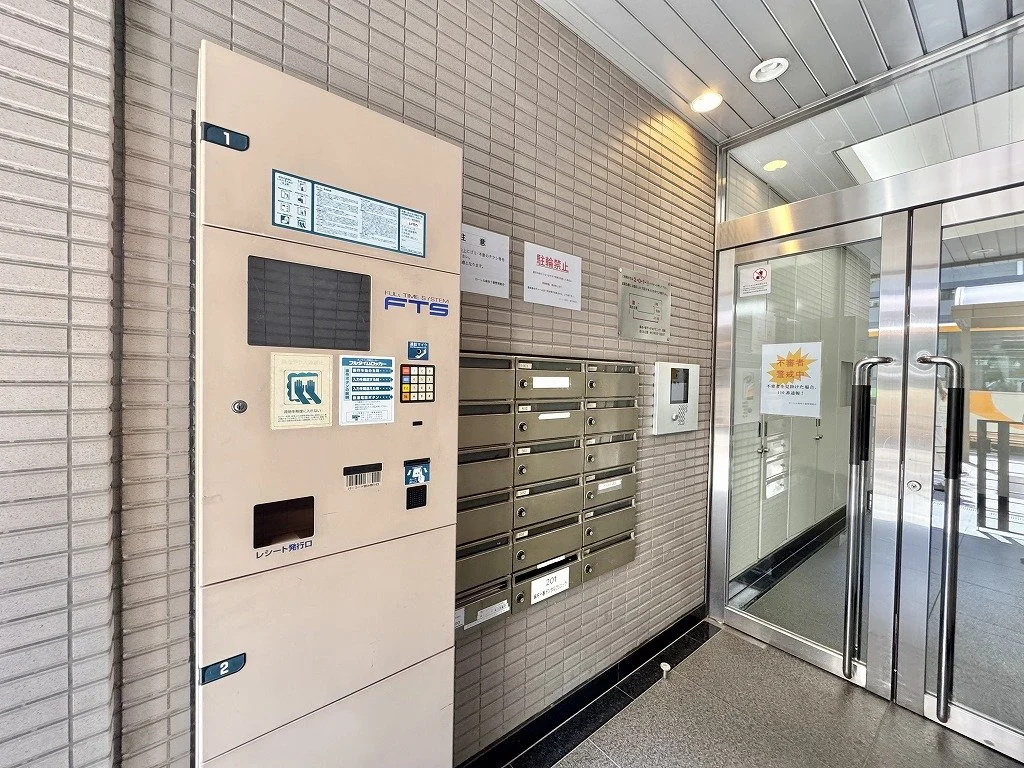郵便ポストと宅配ボックスが設置されている建物の入口付近の様子
