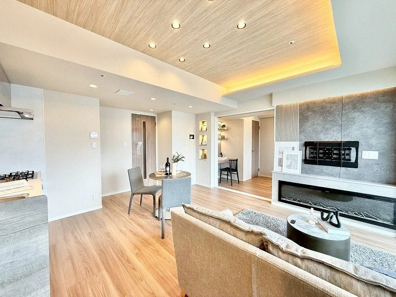 広々としたモダンなリビングルームのインテリア。木製の床と天井のデザイン、ソファやテーブル、テレビなどが配置されている。