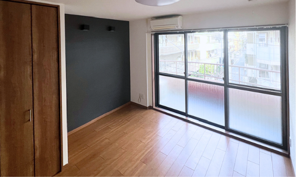 空っぽの部屋で、木製の床と大きな窓、エアコンが設置されている