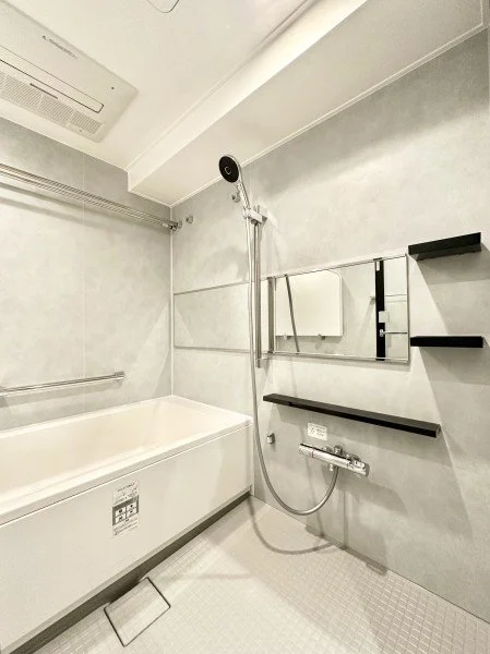 浴槽、シャワー、鏡、棚、手すりが付いたバスルーム