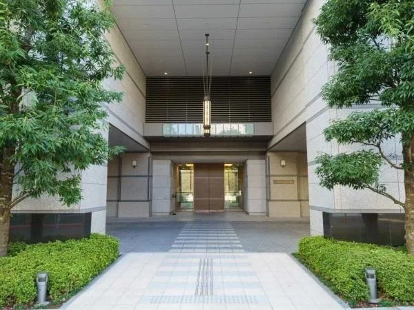 ビルのエントランスの前に植物と緑の生垣がある風景