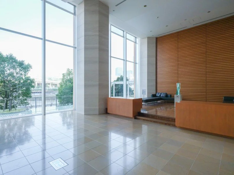 清潔なロビーエリア、ガラス窓から外の景色と緑が見える。木製の待合室とソファが配置されている。