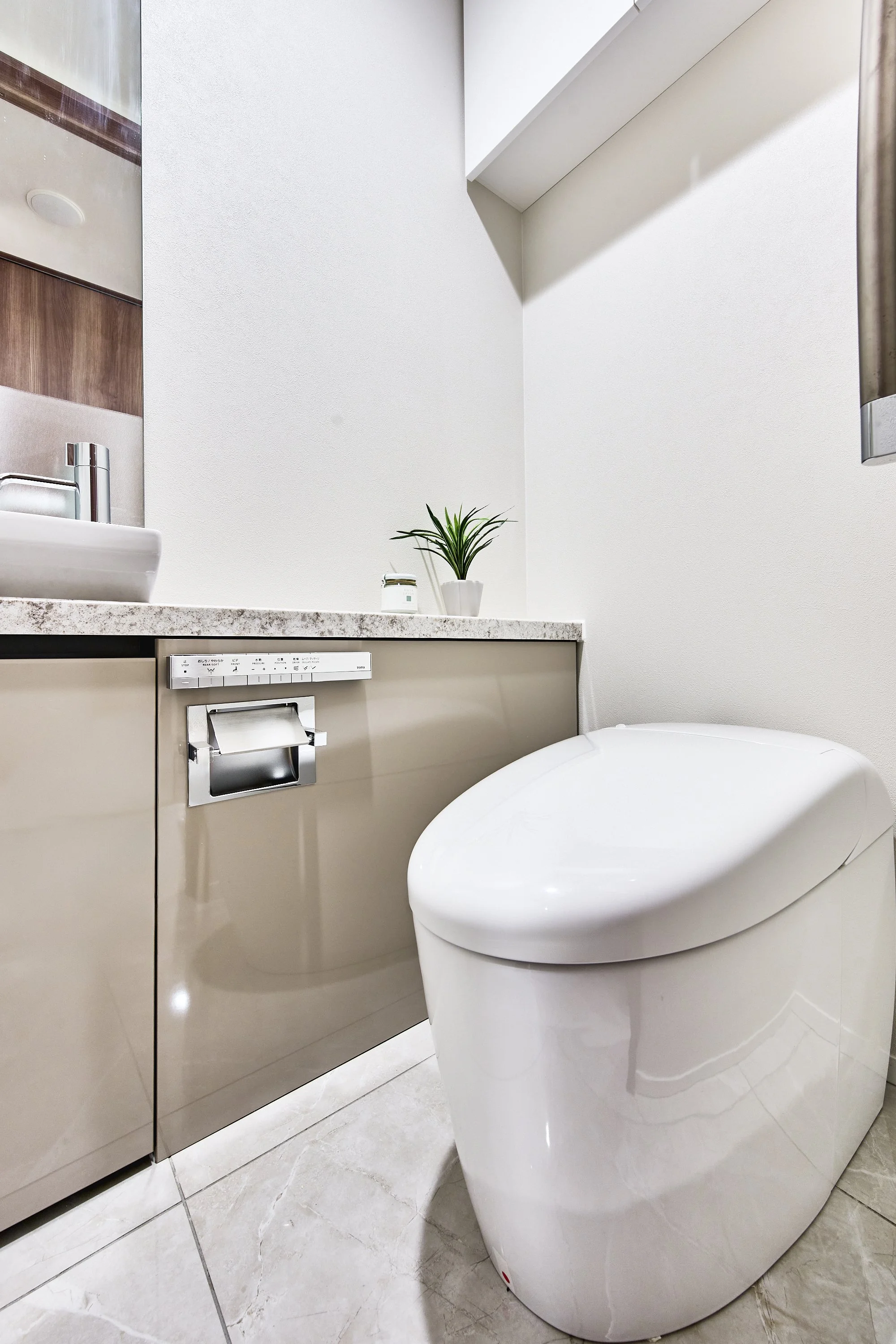 白い便座の便器と、洗面台、木製の扉があるトイレの interior.
