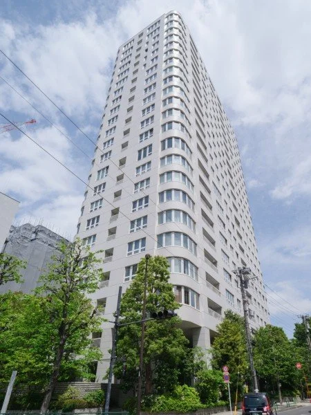 高層の白い建物と周囲の木々、青空