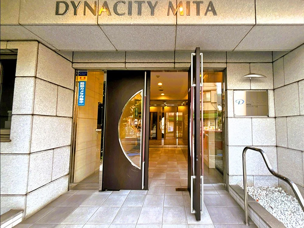 ミタオフィスの入り口の写真。ドアの上に「DYNACITY MITA」の看板があります。