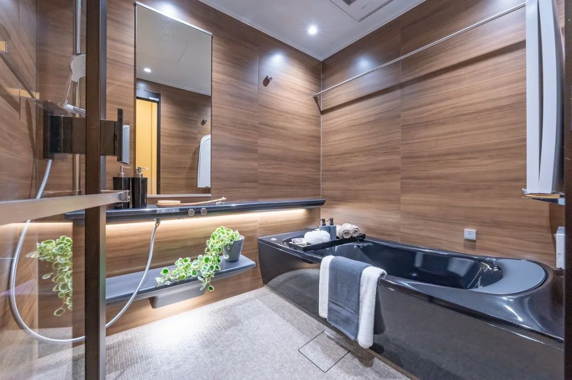木目調の浴室にバスタブ、鏡付きの洗面台、シャワー、タオルとアメニティ。