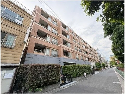集合住宅の建物と歩道、公園の木と低い生垣