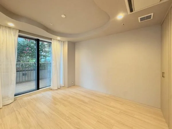 白い壁と木製の床の空き部屋と、窓とカーテン、バルコニーの景色。