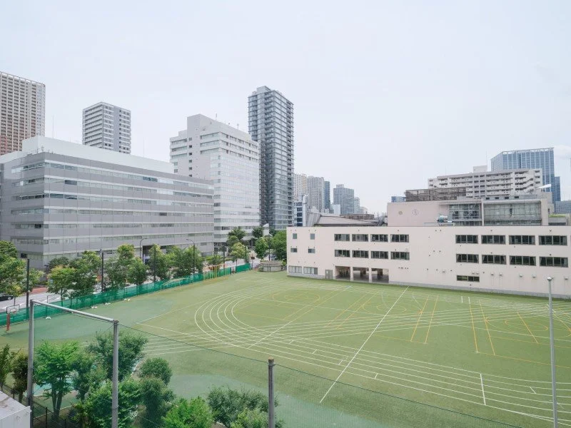都市の中の学校の運動場と高層ビル群