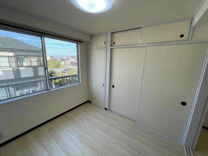 空の部屋で窓から外の景色が見える。壁には収納用の引き戸がある。