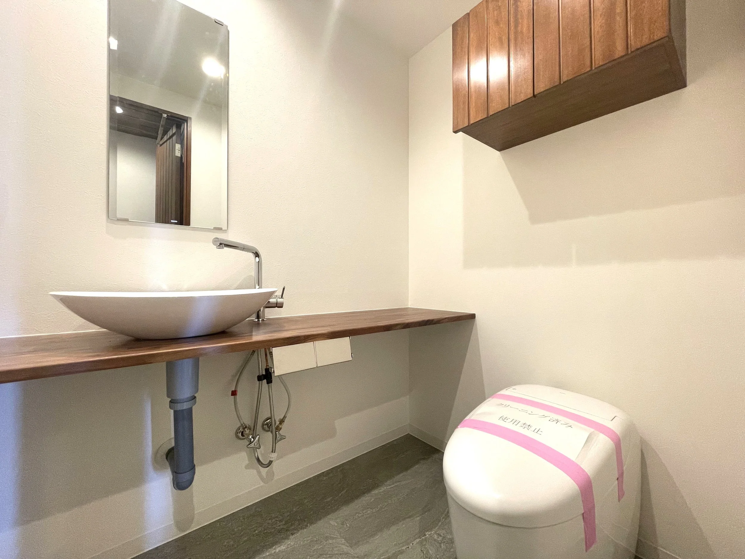 木製の棚と白い洗面ボウル、鏡、トイレ。シンプルでモダンな洗面所の interior.