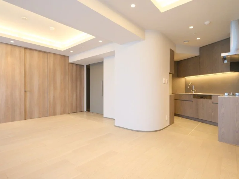 モダンなキッチンとリビングルームの空間、白い壁と木製の収納棚、明るい照明がある室内