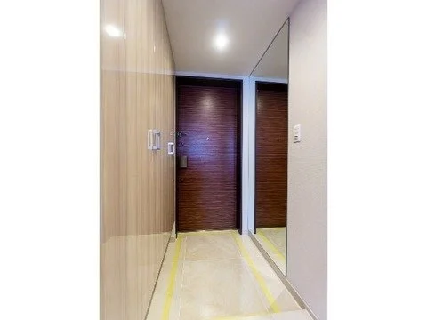 廊下の入り口に木のドアと鏡が設置されたシンプルな室内の写真