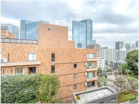 都市の景色で、手前に茶色のマンション、背景に高層ビル群が見える風景