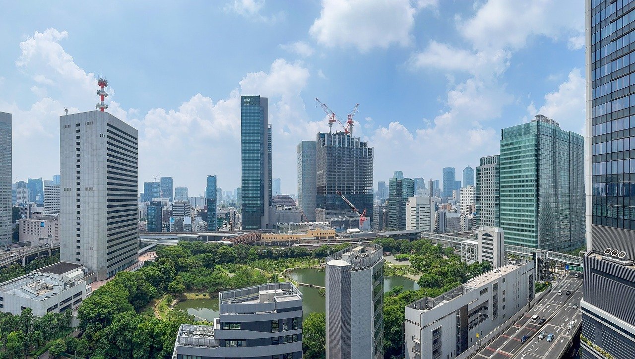 高層ビルが立ち並ぶ都市の景色と中央に小さな池のある緑地公園
