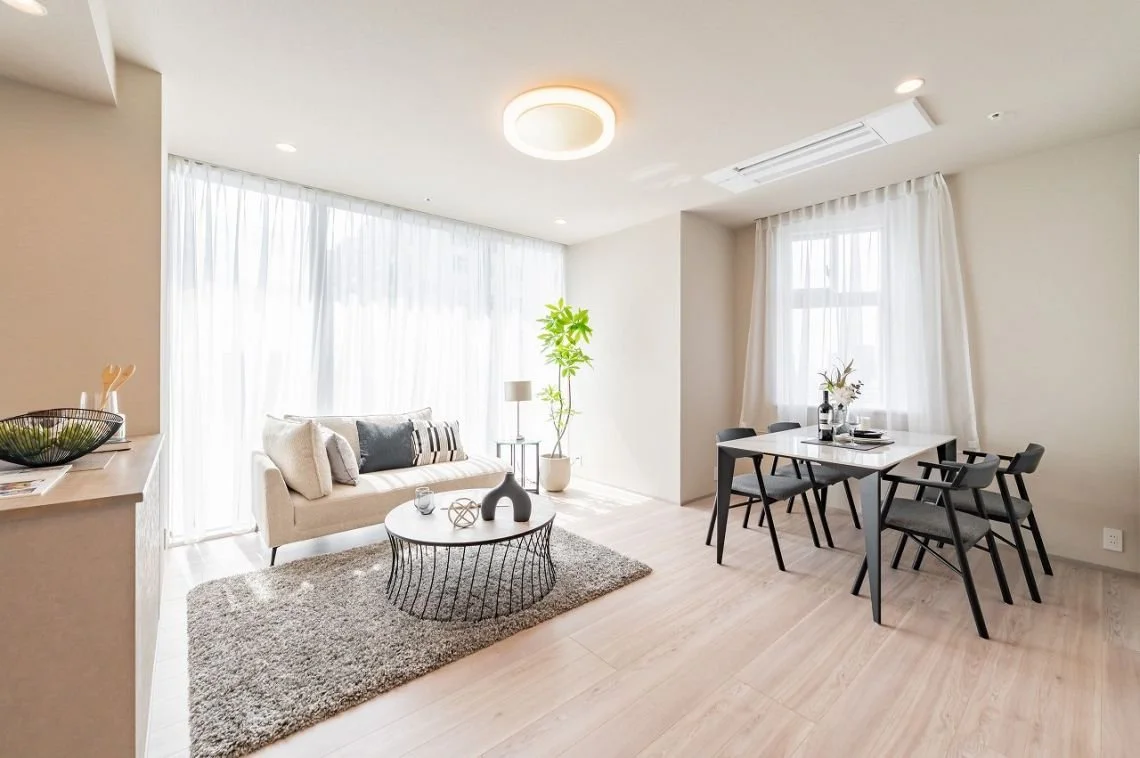 明るいリビングとダイニングルームの interior with ソファー、テーブル、椅子、観葉植物、白いカーテン。現代的なデザインとシンプルな装飾が施された空間。