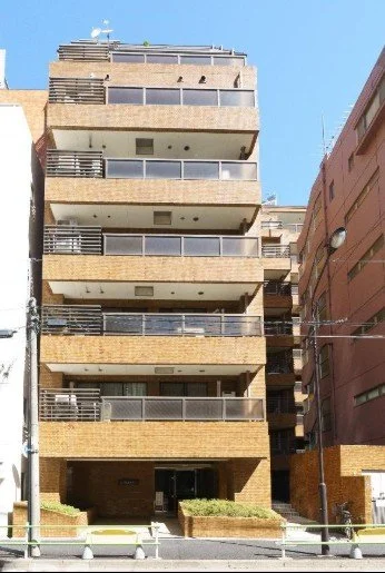 中層のコンクリート造のマンション建物。バルコニーとガラスの手すりがある。