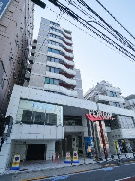 高層ビルと路上の店舗外観、掲示板や電線が見える都市の景観