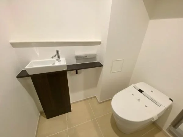 トイレとその横の小さな洗面台があるトイレルームの内観