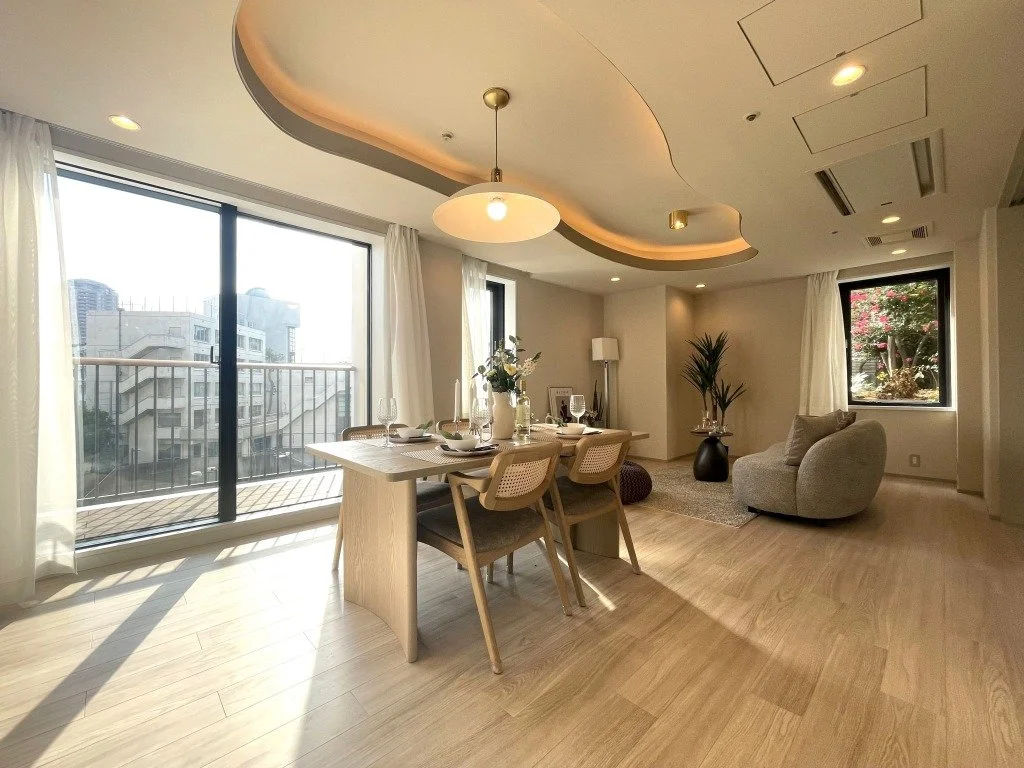 明るいリビングルームとダイニングエリア、バルコニー、観葉植物、ソファと窓から外の景色が見える