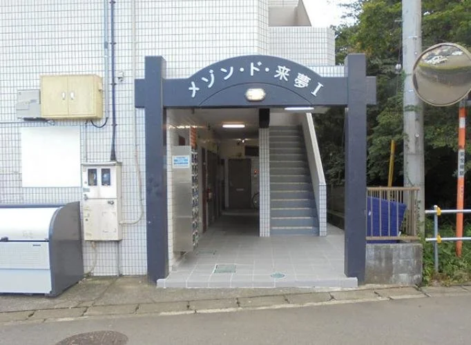 アパートの入り口に看板で書かれた『メゾン・ド・未来 I』の看板と階段が見える写真
