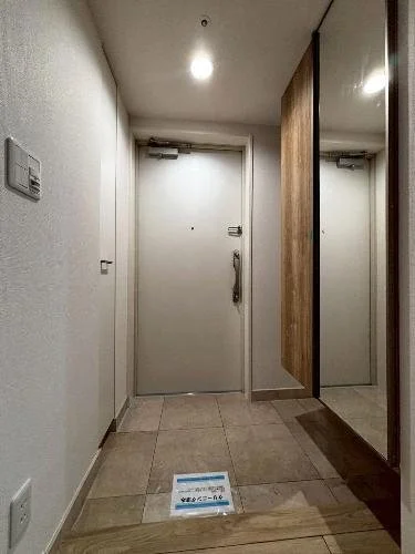 玄関のドアと鏡張りの収納のある廊下の写真
