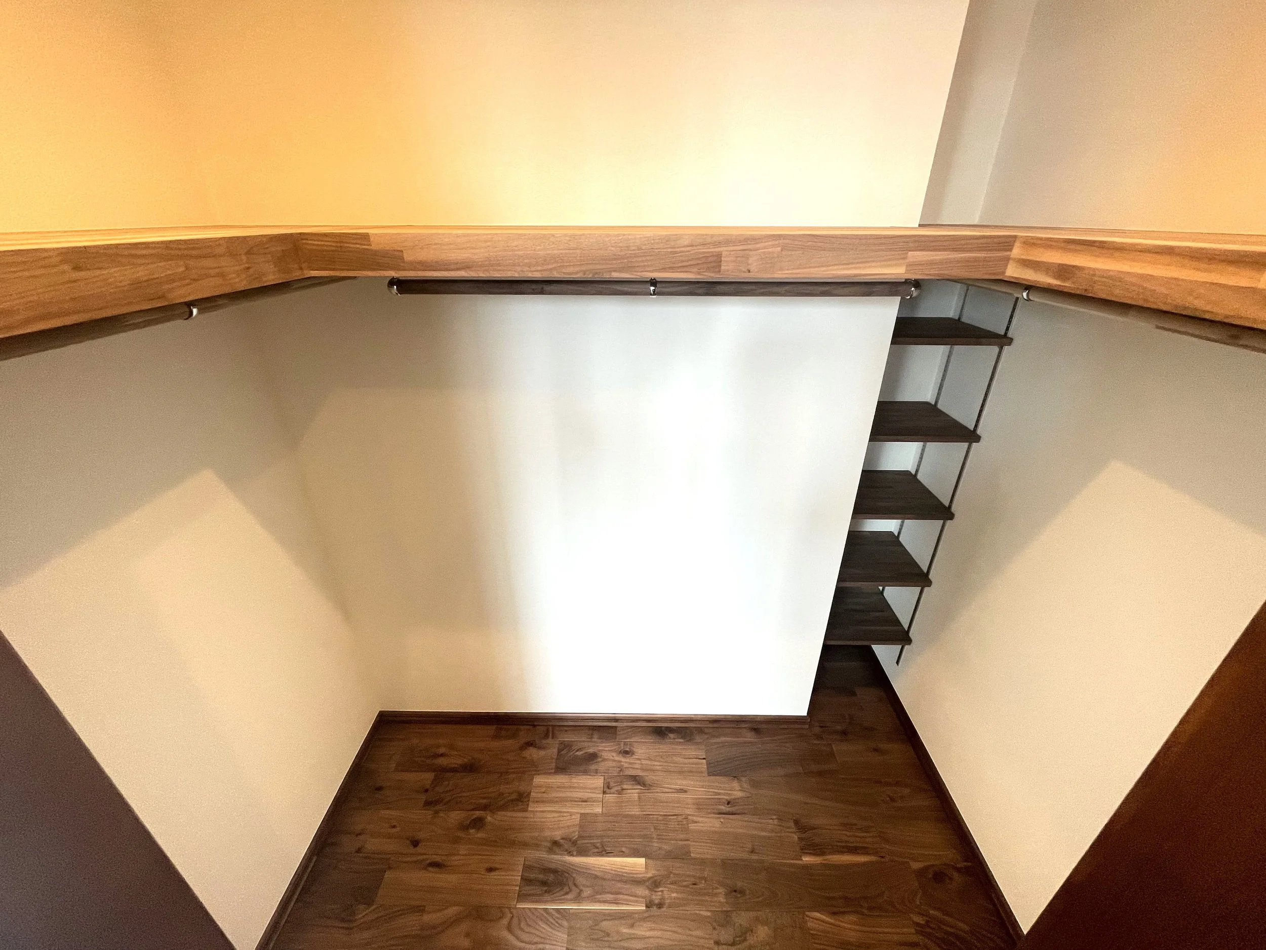 木製の棚と階段がある狭いクローゼットの内部、明るい照明。