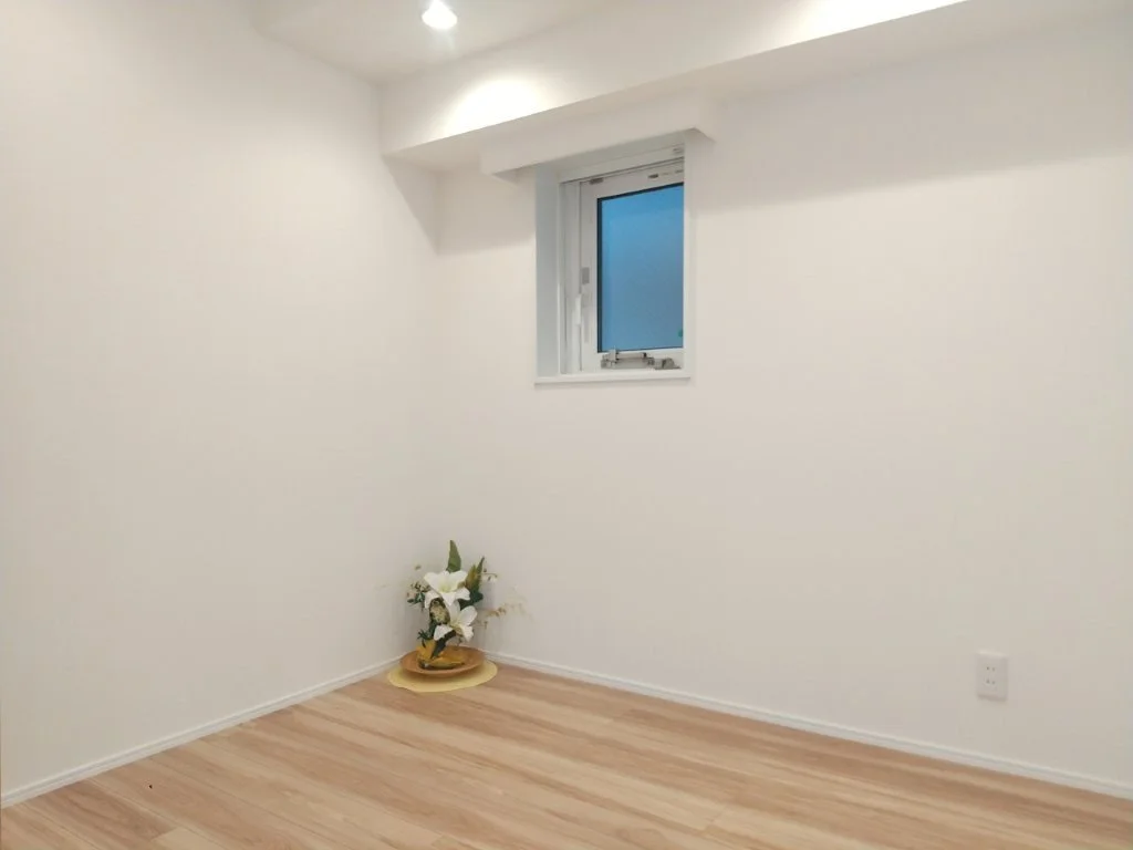 白い壁と木製の床の部屋に花の飾りが置かれている室内。