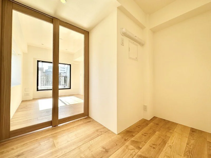 明るい空間の室内、木製の床と白い壁、窓とガラス扉がある部屋