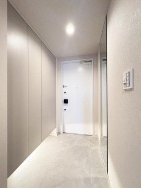 白い壁とドアがあるシンプルな廊下の玄関エリア
