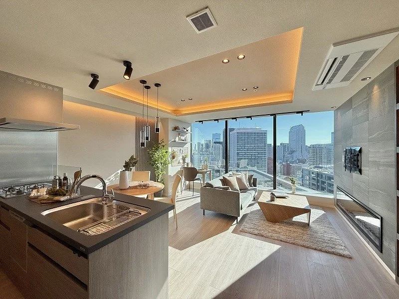 高層ビルが見える都会の新築高級マンションのリビングルームとキッチンの内観写真