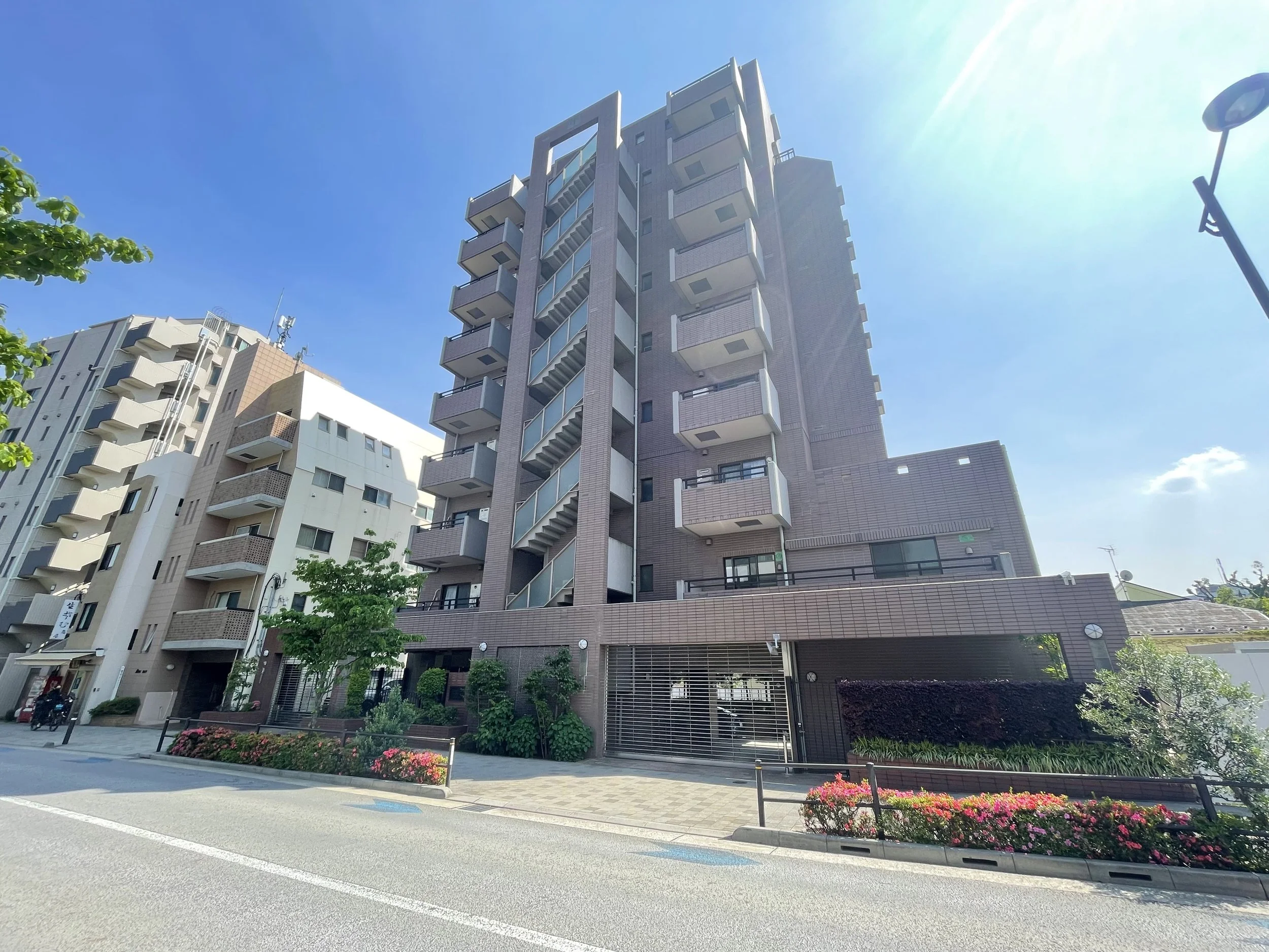 高層のマンション建物と花壇、道路と街灯