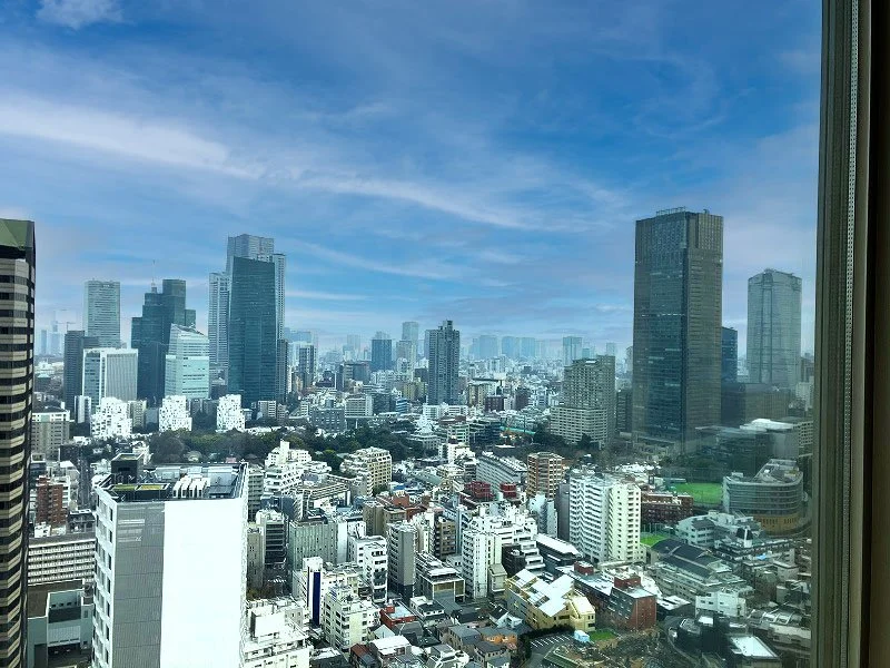 高層ビルの並ぶ都市の景色、青空に雲が漂う