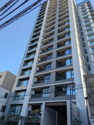 高層の白いコンクリートのマンション建物。窓とバルコニーが並ぶ都市の景観の一部です。