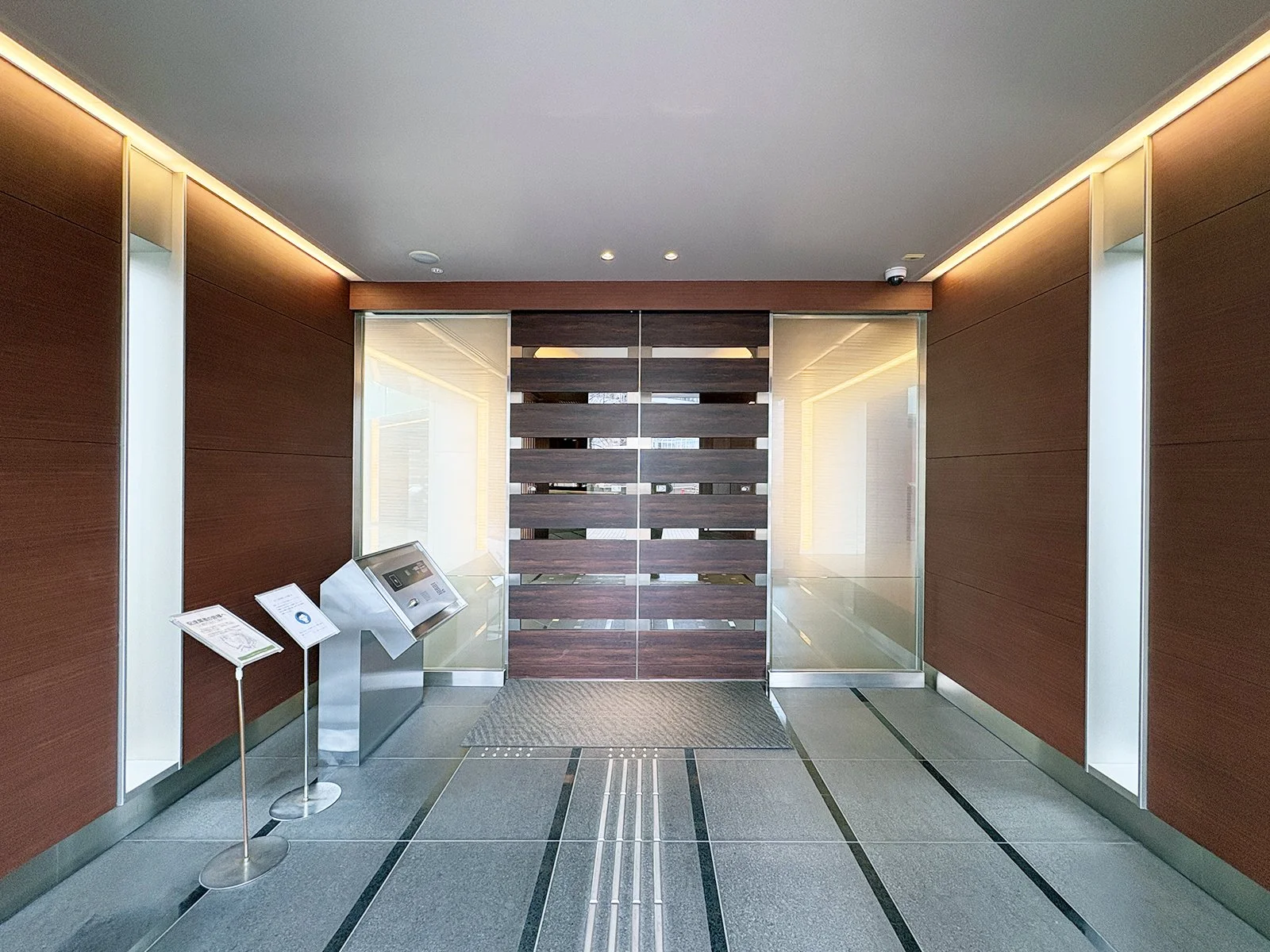 木製のドアとガラスの壁を持つエントランスホールの写真