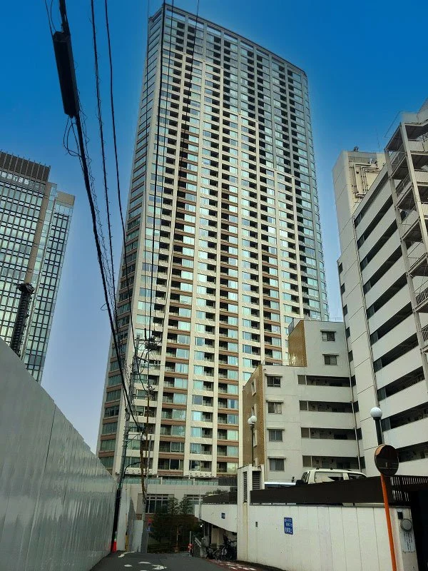 高層ビルが立ち並ぶ都市の景色。青空の下に大きなガラス張りの建物。