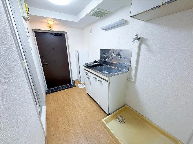 小さなキッチンと洗濯機置き場があるシンプルな部屋の画像