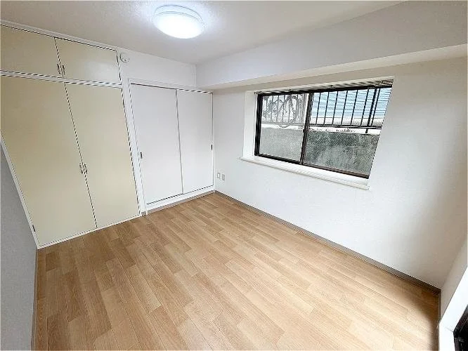 空の部屋、白い壁と木製の床、窓には格子がある。